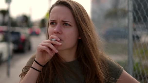Młoda kobieta zagubiona w myślach pali papierosa — Wideo stockowe
