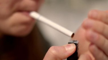 Tatmin olmamış genç bir kadın sigara yakıyor.