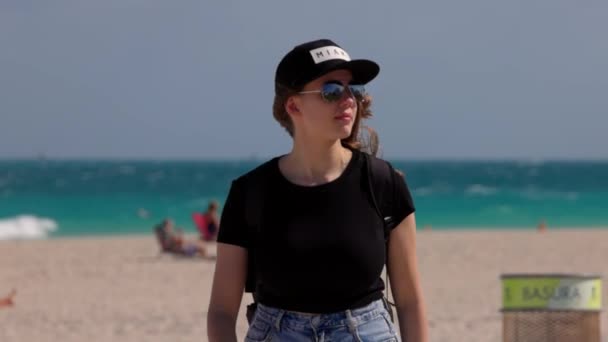 ผู้หญิงสวยเดินไปตามชายหาดไมอามี่ในวันที่แดด — วีดีโอสต็อก