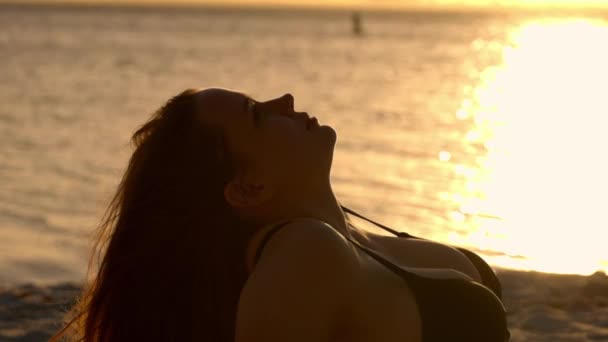 Relaxando na praia ao pôr do sol desfrutando dos raios de sol quentes sobre o oceano — Vídeo de Stock