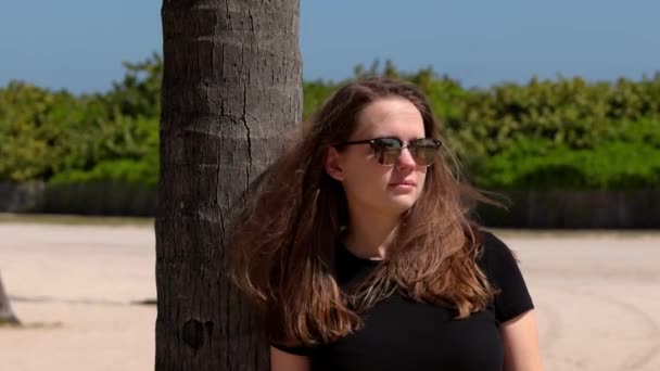 迈阿密海滩的一位年轻女子靠在棕榈树上 — 图库视频影像