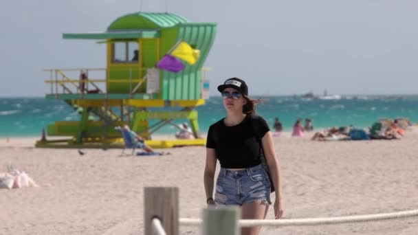 Güzel bir kadın güneşli bir günde Miami sahilinde yürür. — Stok video