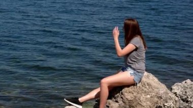 Florida Keys 'in sakin sularında bir kayanın üzerinde oturan güzel kadın.