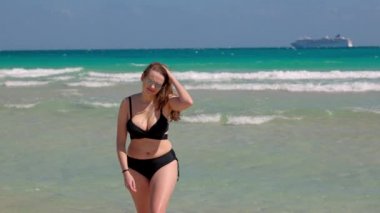 Rüzgarlı bir günde Miami Plajı 'nda bikini giyen genç ve güzel bir kadın.