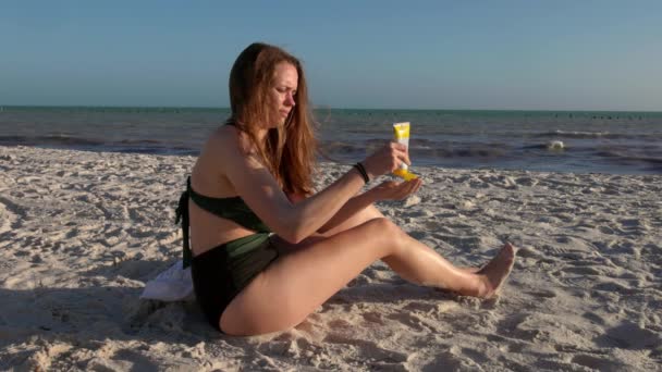 Ung kvinna använder solskydd på stranden — Stockvideo