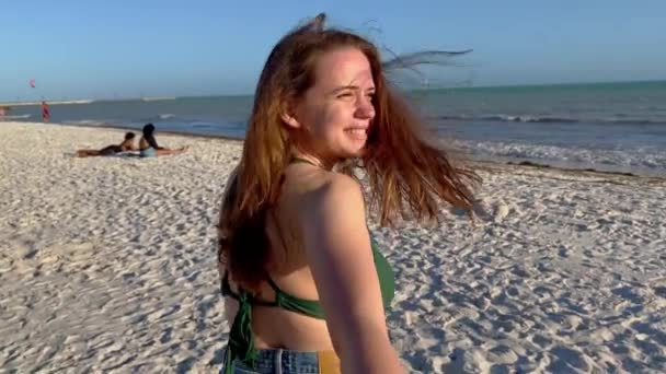 Jovem mulher puxa seu namorado através de uma praia — Vídeo de Stock