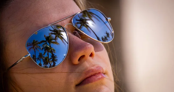 Rosto de uma menina bonita com sungalsses espelhando palmeiras — Fotografia de Stock