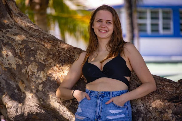 Schöne junge Frau posiert an einer Palme am Miami Beach — Stockfoto