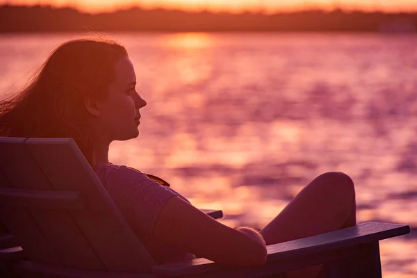 Jonge vrouw zit op het strand en geniet van de zonsondergang over de zee — Stockfoto