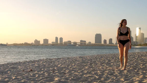 Mladá žena v bikinách na pláži při západu slunce nad Miami — Stock fotografie