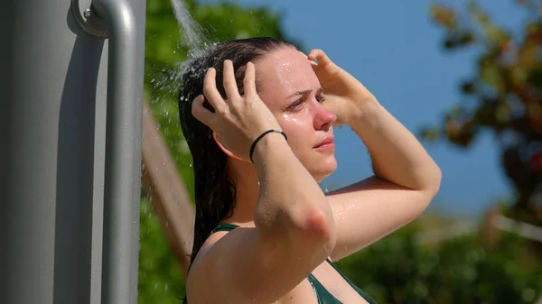Jeune femme prenant une douche après un bain de soleil à la plage — Photo