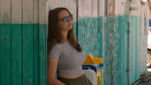 Muotokuva nuoresta kauniista naisesta nojaamassa seinää vasten kesällä — kuvapankkivalokuva