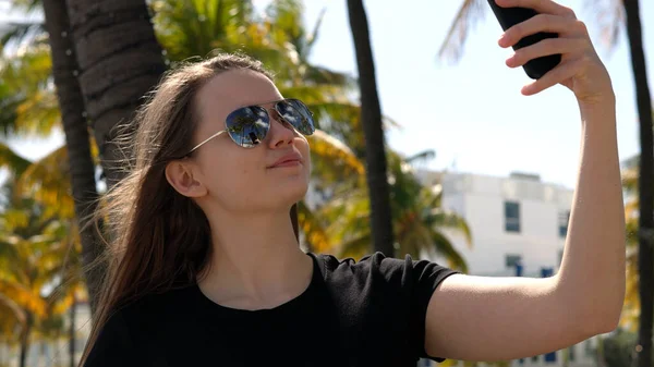 Jeune femme prenant un selfie sous les palmiers à la plage — Photo