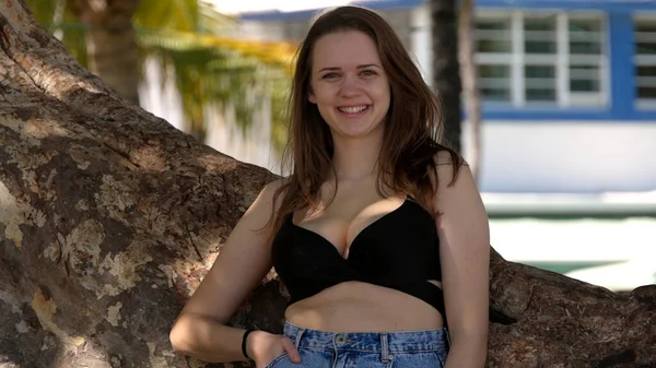 Jovem mulher sexy encostada a uma palmeira na praia — Fotografia de Stock
