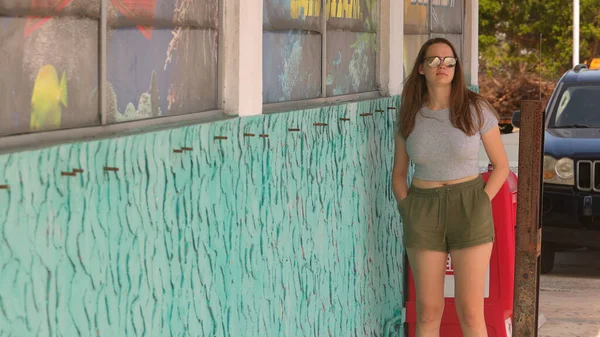 Muotokuva nuoresta kauniista naisesta nojaamassa seinää vasten kesällä — kuvapankkivalokuva