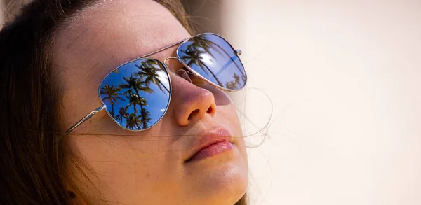 Rosto de uma menina bonita com óculos de sol espelhando palmeiras — Fotografia de Stock