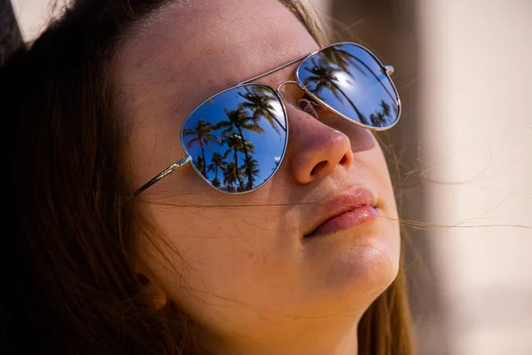 Volto di una bella ragazza con occhiali da sole che rispecchiano palme — Foto Stock