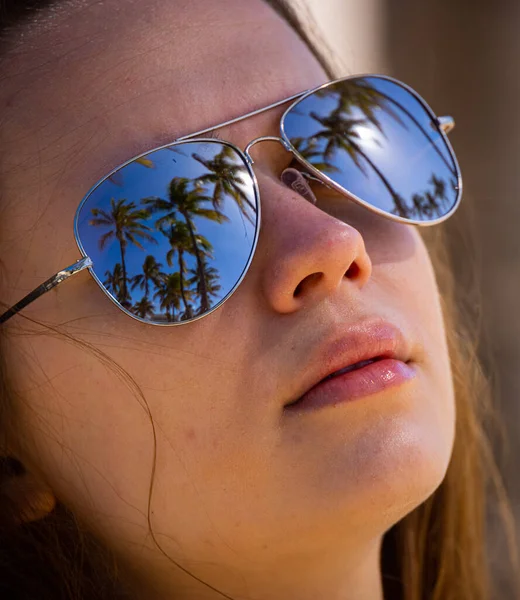 Rosto de uma menina bonita com óculos de sol espelhando palmeiras — Fotografia de Stock