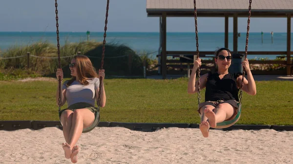 Deux jeunes femmes sur une balançoire s'amusent — Photo