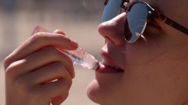 Genç kadın dudak parlatıcısı sürüyor. Yakın çekim.