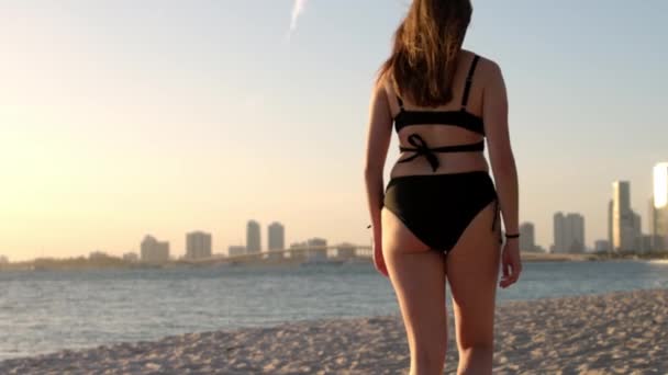 Jonge vrouw draagt een bikini op het strand bij zonsondergang boven Miami — Stockvideo