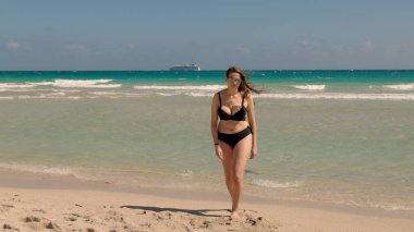 Rüzgarlı bir günde Miami Plajı 'nda bikini giyen genç ve güzel bir kadın.