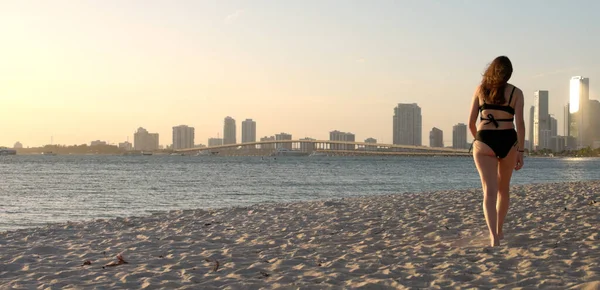 Jovem mulher vestindo um biquíni na praia ao pôr do sol sobre Miami — Fotografia de Stock