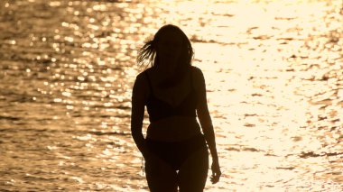 Güzel bir kadın gün batımında Miami 'de sıcak okyanus suyunun tadını çıkarıyor.