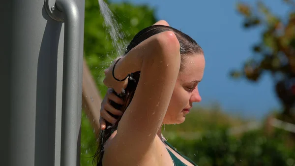 Ung kvinna som duschar efter att ha solat på stranden — Stockfoto