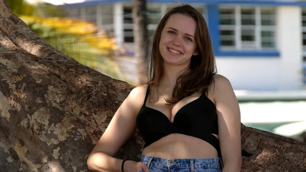 Jovem mulher sexy encostada a uma palmeira na praia — Fotografia de Stock