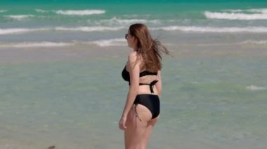 Rüzgarlı bir günde Miami Plajı 'nda bikini giyen genç ve güzel bir kadın.
