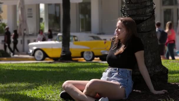 Молодая женщина отдыхает на солнце на набережной Майами Саут Бич — стоковое видео