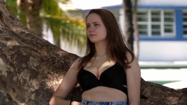 Mladá sexy žena opírající se o palmu na pláži — Stock video