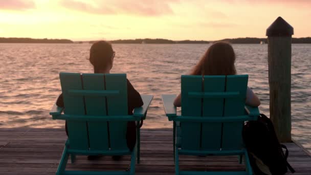 Dos mujeres se sientan en una tumbona y disfrutan de la puesta de sol — Vídeo de stock