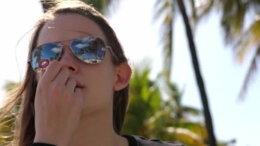 Kız güneşli bir günde dudak parlatıcısı sürüyor.