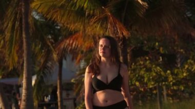 Miami 'de gün batımında plajda bikini giyen genç bir kadın.