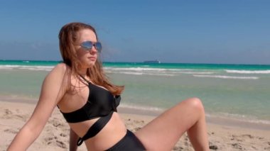 Genç bir kadın Miami Sahili 'nde güneşin tadını çıkarıyor.