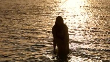 Güzel bir kadın gün batımında Miami 'de sıcak okyanus suyunun tadını çıkarıyor.