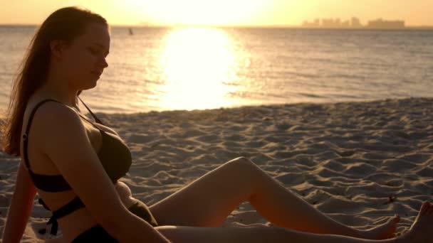 若い女性は日没時にビーチで砂と遊ぶ-スローモーション — ストック動画
