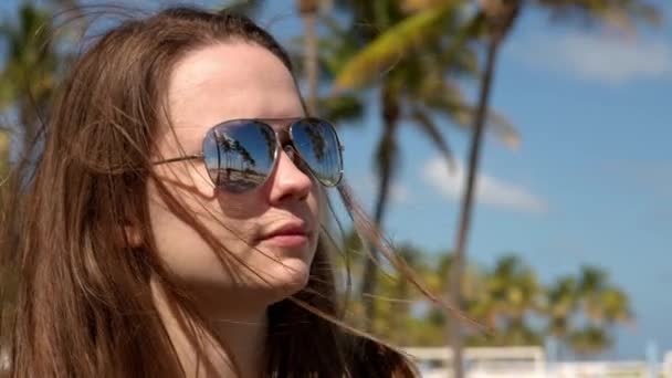 Крупним планом знімок красивої дівчини під пальмами на пляжі — стокове відео