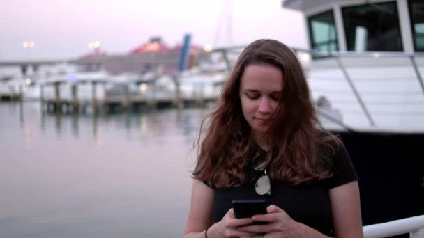 Mujer joven escribiendo mensajes de texto en su teléfono celular en el Puerto de Miami — Vídeo de stock