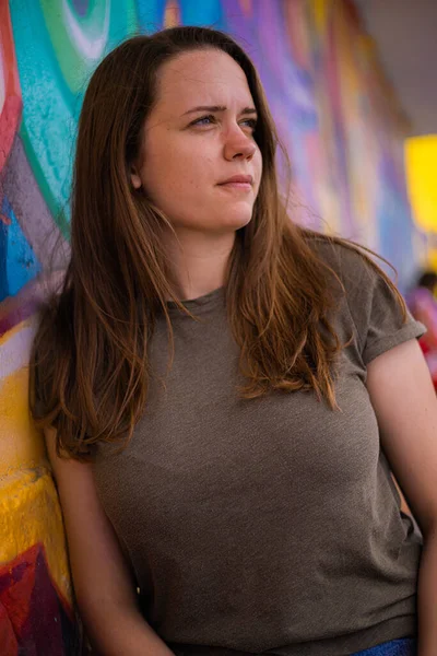 Jeune et belle femme se penche contre un mur coloré et pose pour la caméra - style de rue typique — Photo