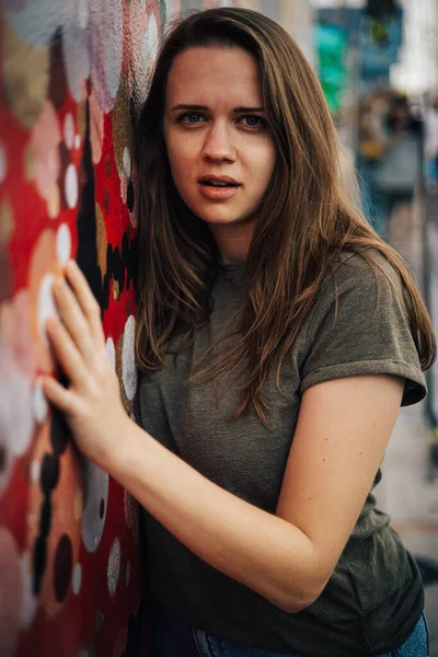 Sokaklarda güzel bir kızın renkli bir duvara karşı portresi. Sokak tarzı fotoğrafçılık. — Stok fotoğraf