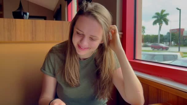 Jonge vrouw die het ontbijtmenu in een restaurant bekijkt - MIAMI, VERENIGDE STATEN - FEBRUARI 20, 2022 — Stockvideo