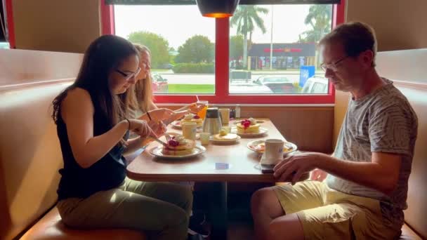 Group of people eating breakfast at a restaurant - MIAMI, UNITED STATES - FEBRUARY 20, 2022 — Stock Video