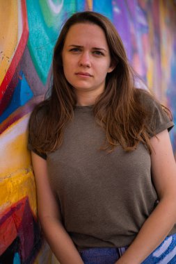 Sokaklarda güzel bir kızın renkli bir duvara karşı portresi. Sokak tarzı fotoğrafçılık.