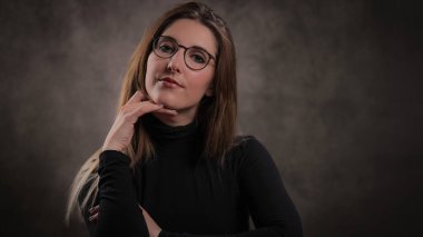 Koyu gri arka planda genç ve çekici bir kadının yakın çekimi.