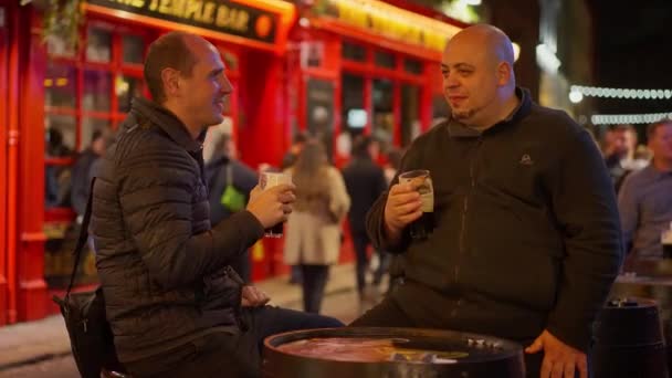 Dwóch przyjaciół pijących piwo w dzielnicy Temple Bar w Dublinie nocą - zdjęcia z wakacji — Wideo stockowe