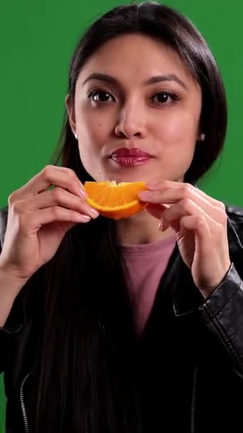 年轻女人咬着一片橘子工作室拍摄的照片 — 图库视频影像