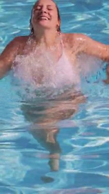 Güneşli bir günde bikinili seksi kız havuzda eğleniyor.